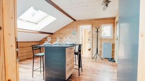 A cozy, wooden-paneled room with a central island table, two chairs, and a skylight. - L'Ecureuil apartment, Finnish bath on the edge of the forest. Pets allowed (Gérardmer)