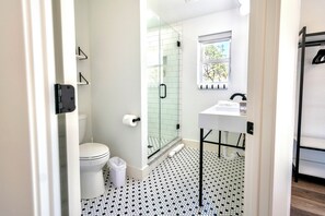 Et moderne badeværelse med toilet, bruser og vask.