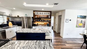 Een moderne keuken met een marmeren aanrecht, een 'Cream & Sugar' bord en een koffieapparaat.