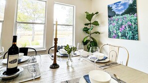 Et spisebord dækket med tallerkener, glas og en vinflaske, med et stearinlys og en plante på bordet.