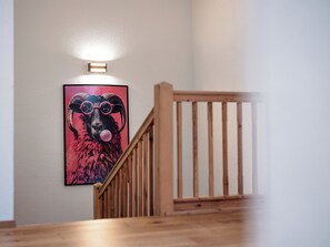 A staircase with a wooden handrail and a wall-mounted light fixture. - Chalet Pirchhof by MYALPS  (Sautens)