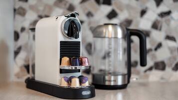 Una cafetera con varios cápsulas de café y una jarra de vidrio sobre una encimera.