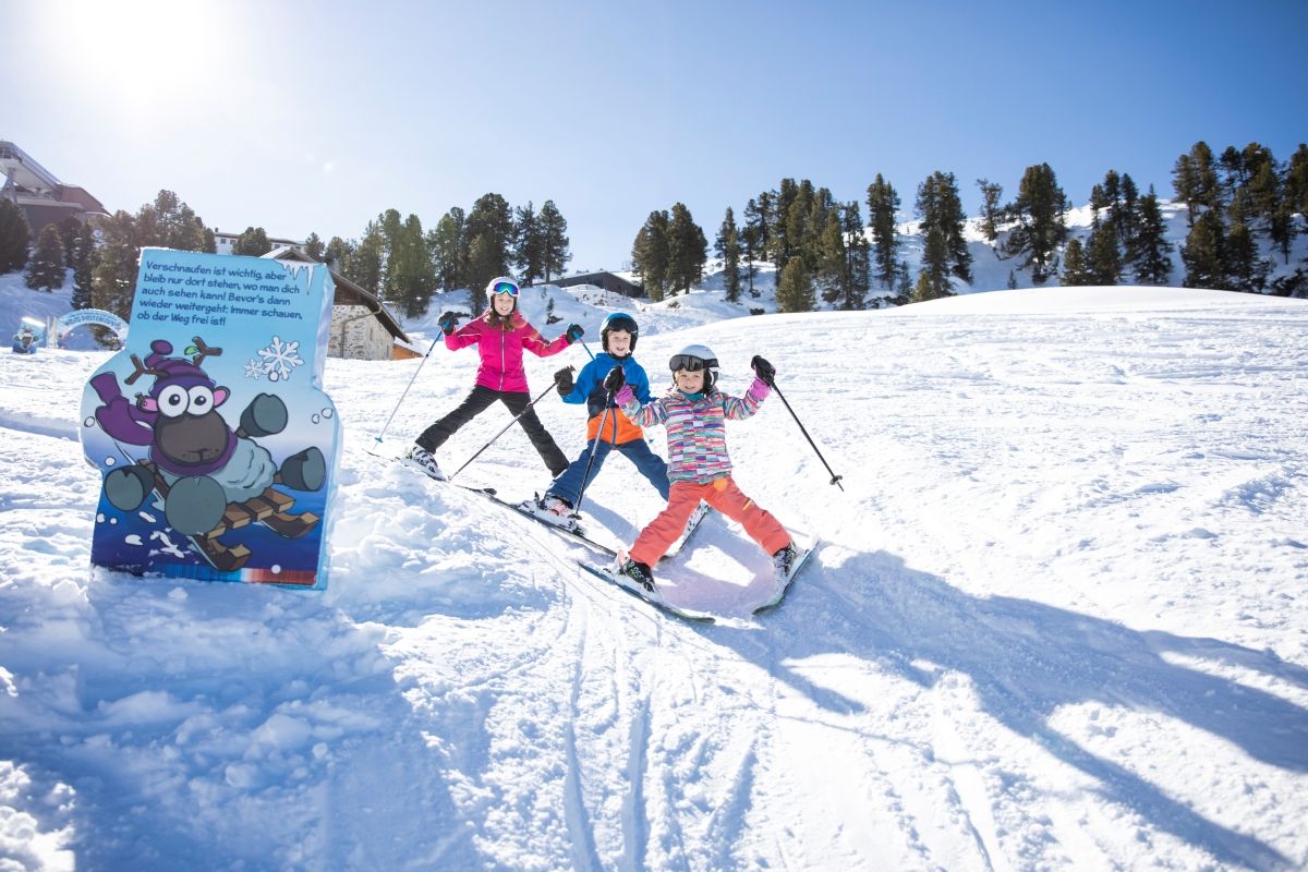 A snowy ski slope with a sign featuring cartoon characters and text.