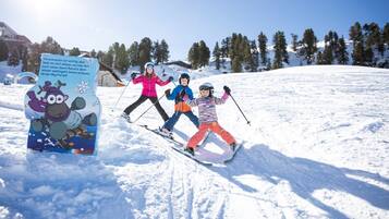 A snowy ski slope with a sign featuring cartoon characters and text.