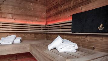 A sauna room with wooden benches and benches, a black towel rack with a logo, and a red light strip.