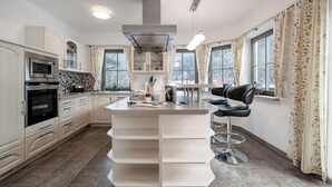 A modern kitchen with a central island, built-in appliances, and large windows. - Chalet Pirchhof by MYALPS  (Sautens)