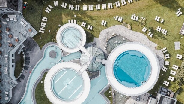 An aerial view of a hotel with multiple swimming pools, lounge areas, and a parking lot. - Chalet Pirchhof by MYALPS  (Sautens)