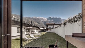 A patio with a grill, a pot, and a towel, overlooking a mountain landscape. - Chalet Pirchhof by MYALPS  (Sautens)