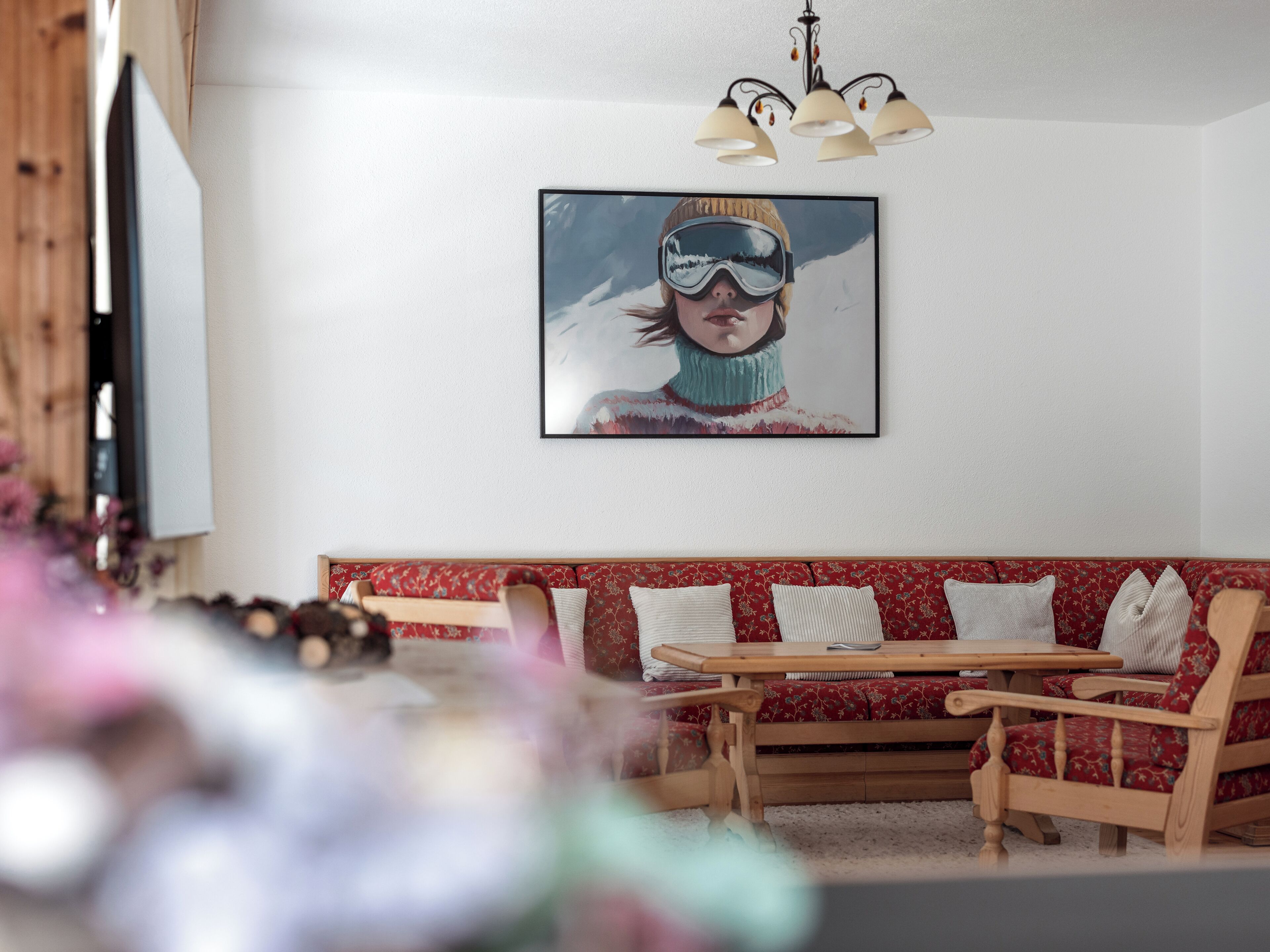 Una sala de estar con un sofá rojo estampado, una mesa de centro de madera y un cuadro enmarcado en la pared.