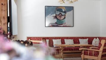 Una sala de estar con un sofá rojo estampado, una mesa de centro de madera y un cuadro enmarcado en la pared.