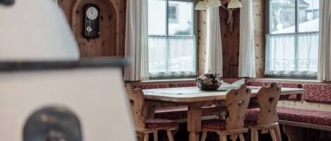 A wooden dining area with a bench, a table, and a clock on the wall.