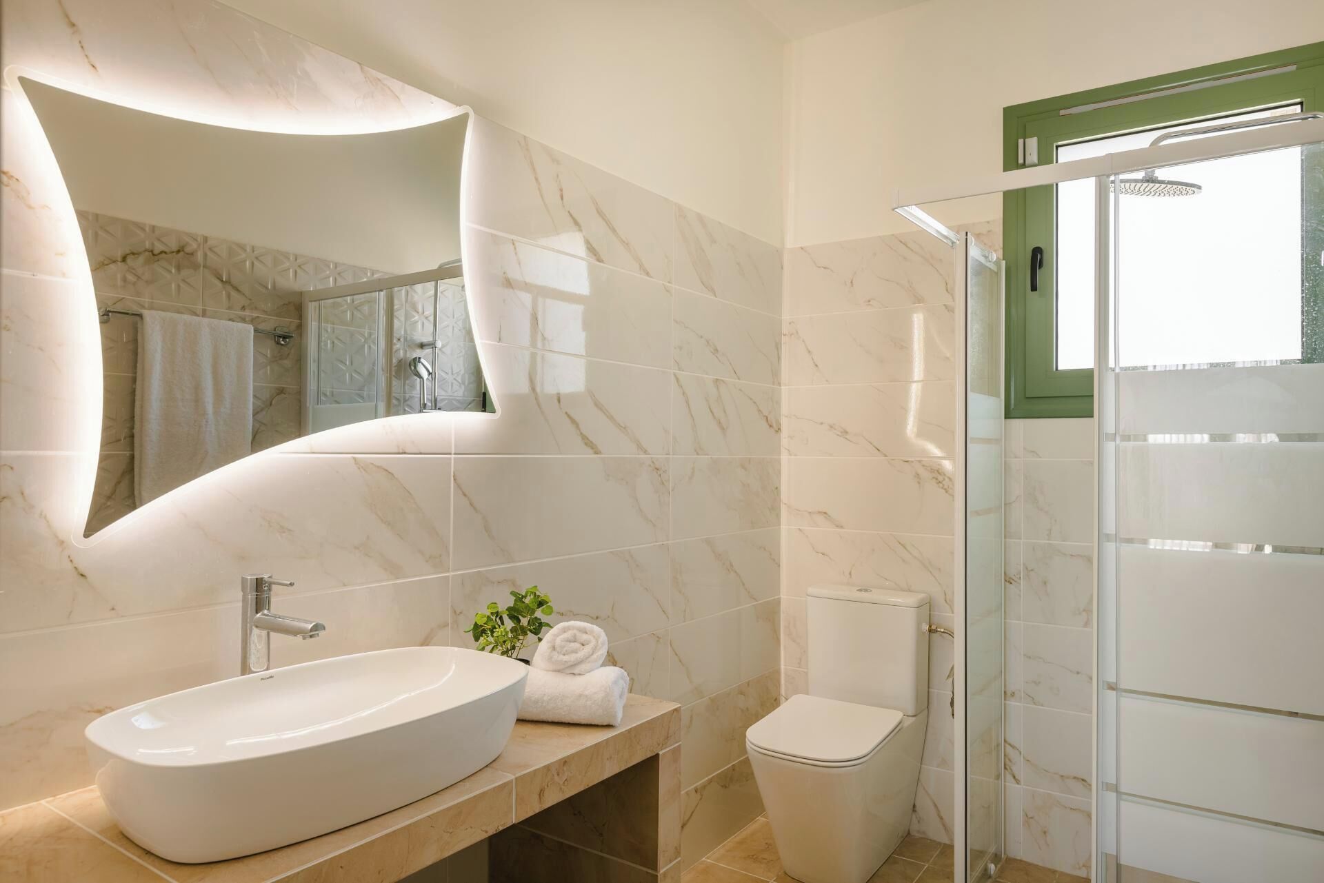 A modern bathroom with a large oval sink, a toilet, and a glass-enclosed shower.