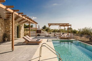 A rooftop pool area with lounge chairs, a pergola, and a stone wall. - Athina Villa - Three Bedroom Villa, Sleeps 6 (Karavados)