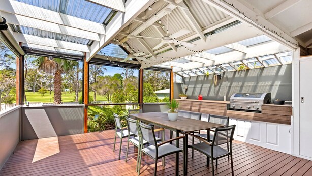 A covered outdoor dining area with a table and chairs, a grill, and a view of a park. - Nordic Fairway - Pet Friendly - 10 mins to Hyams Beach (Sanctuary Point)