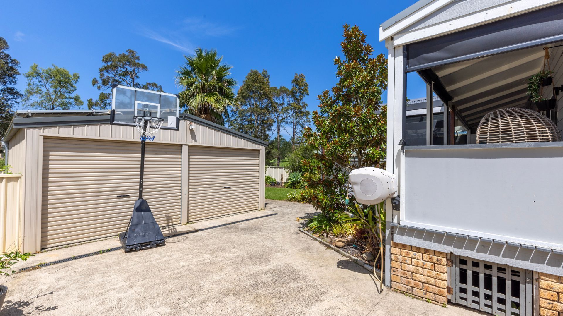 A residential property with a garage, a basketball hoop, and a covered outdoor area.