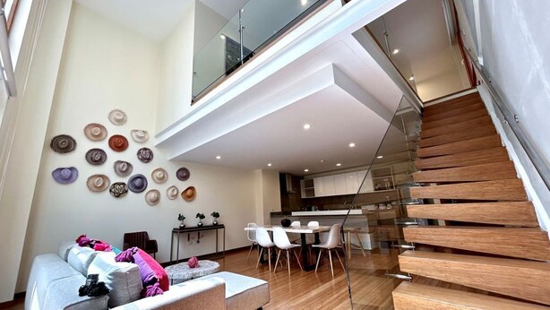 Un intérieur moderne avec un escalier, un coin repas et un mur décoré de chapeaux.