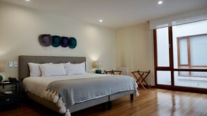 Une chambre avec un grand lit, une table de chevet, un bureau et une chaise. Il y a une fenêtre donnant sur l’extérieur.