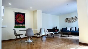 Un salon moderne avec un plancher en bois, un canapé bleu et un coin repas avec deux chaises.