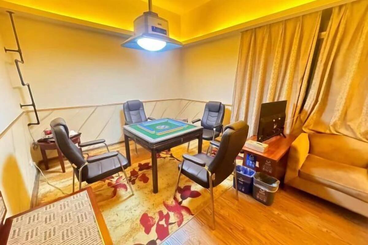 Una habitación con una mesa, cuatro sillas, un sofá, un televisor y una lámpara en el techo.