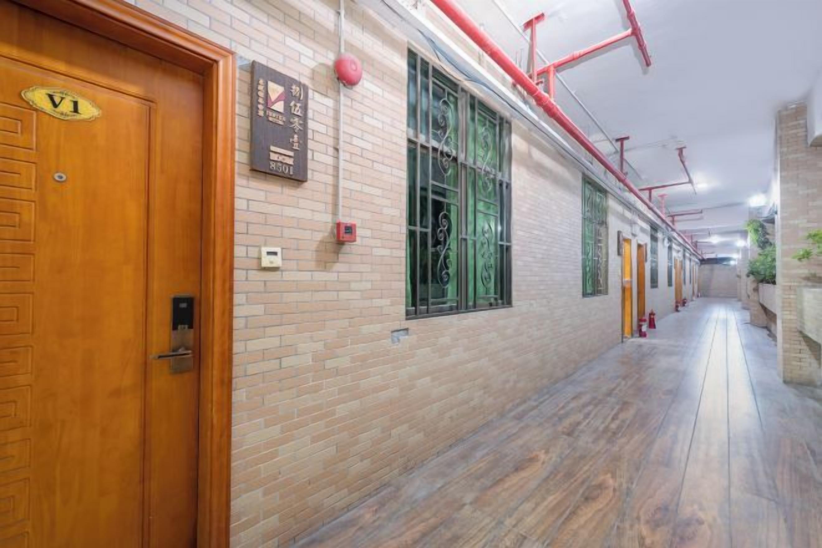 A corridor with wooden doors, a brick wall, and a wooden floor.