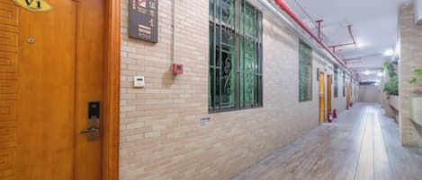A corridor with wooden doors, a brick wall, and a wooden floor.