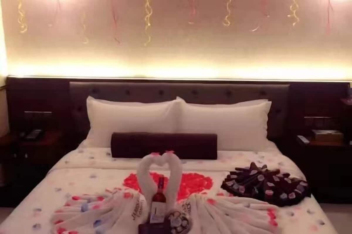 Una habitación de hotel con una cama bien hecha, una almohada, una mesita de noche y una pared con detalles decorativos.