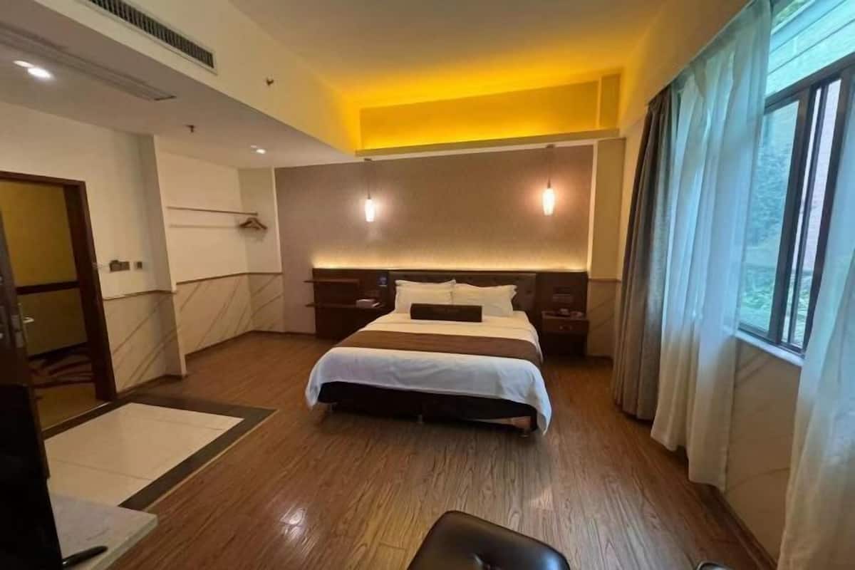 Una habitación de hotel con una cama grande, mesitas de noche, un escritorio y una silla.