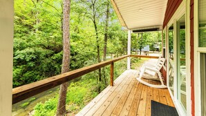 A wooden deck with a railing overlooking a forested area.