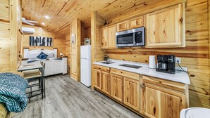 A wooden-paneled kitchen with a microwave, coffee maker, and white refrigerator.