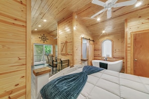 A wooden cabin interior with a bed, a bathroom, and a dining area. - Pam's Treehouse Cabin #3 - Cozy treehouse cabin right on a creek! (Hot Springs)