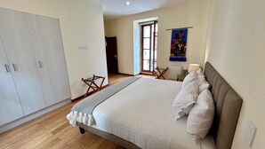 A bedroom with a large bed, a wardrobe, a drying rack, and a view of the outside. - La Ronda 431 - Apt. #104 (Quito)
