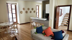 A living room with a sofa, coffee table, and chairs. There is a kitchen area with a counter and stools. - La Ronda 431 - Apt. #104 (Quito)