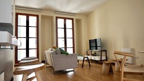 A spacious living room with a sofa, a TV, and a wooden dining table. - La Ronda 431 - Apt. #104 (Quito)