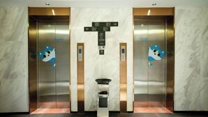 Two elevators with directional signs and a small trash bin in the center. - City Comfort Inn(Wuhan Jiangxia Branch) (Wuhan)