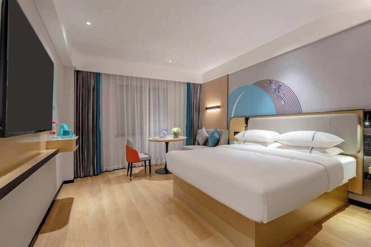 A modern hotel room with a large bed, a desk, and a chair.