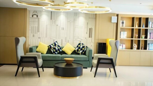 A modern living room with a sofa, two armchairs, a coffee table, and a bookshelf. - City Comfort Inn(Wuhan Jiangxia Branch) (Wuhan)