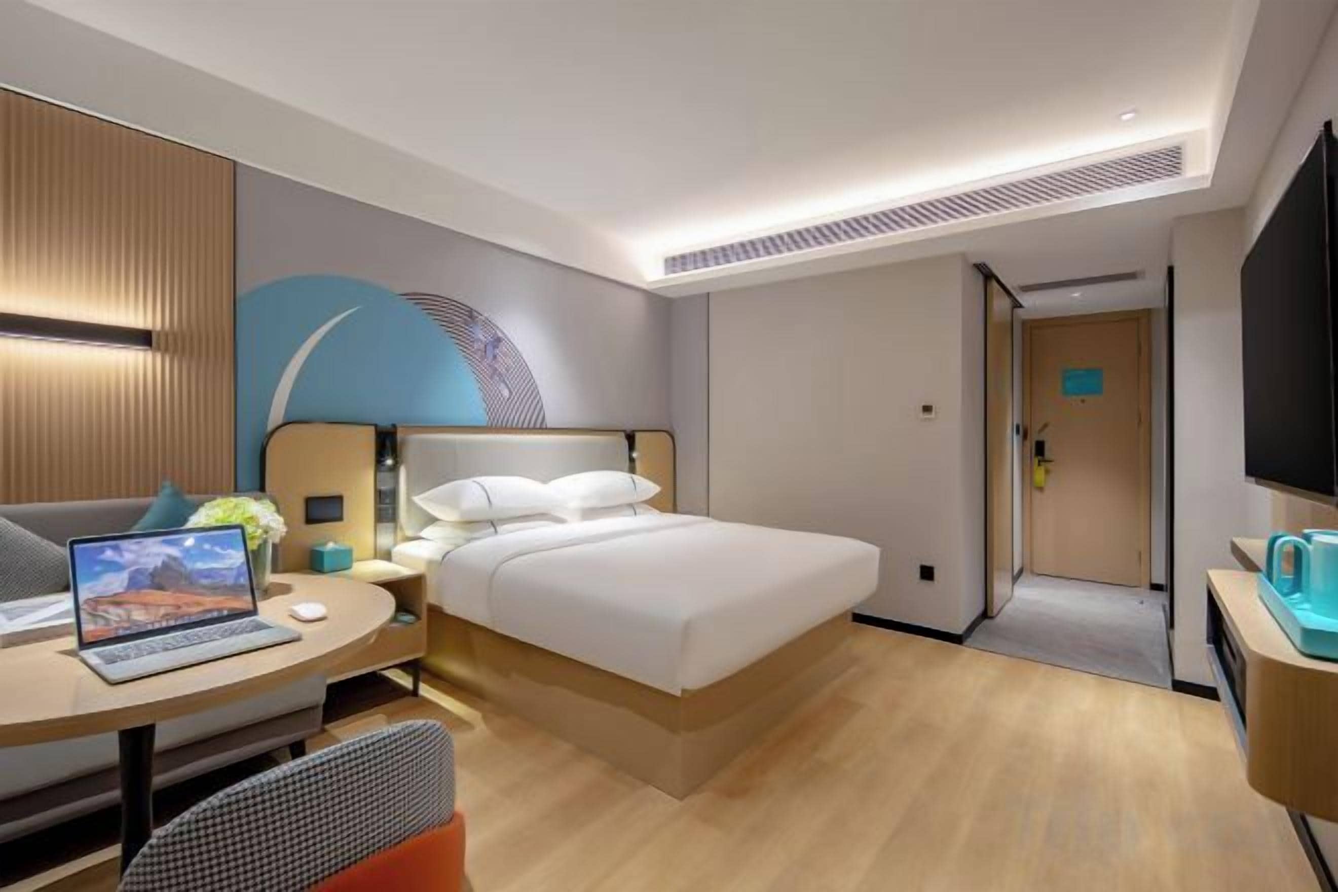 A modern hotel room with a bed, desk, and seating area.