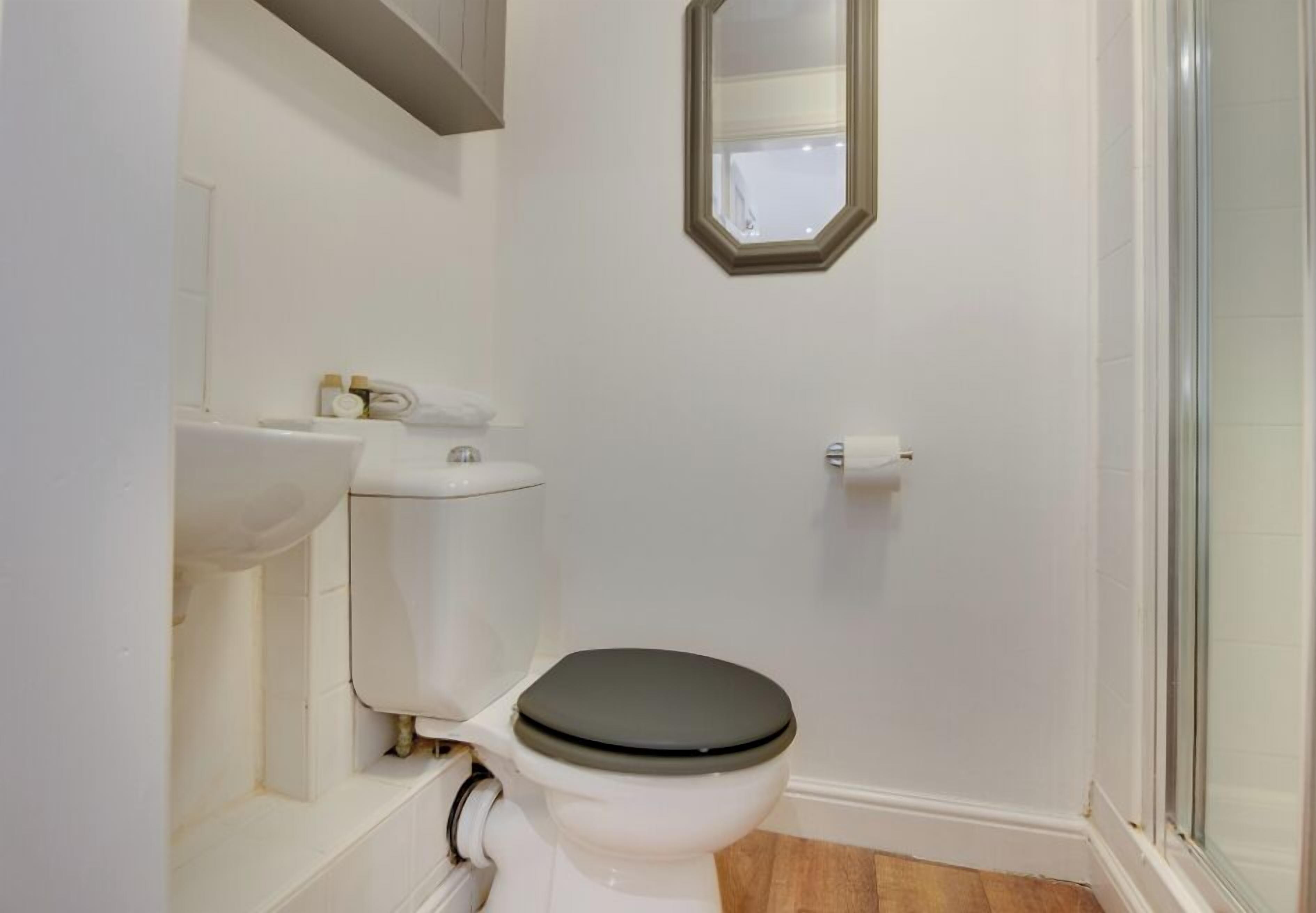 Un baño pequeño y limpio con inodoro, lavabo y ducha.