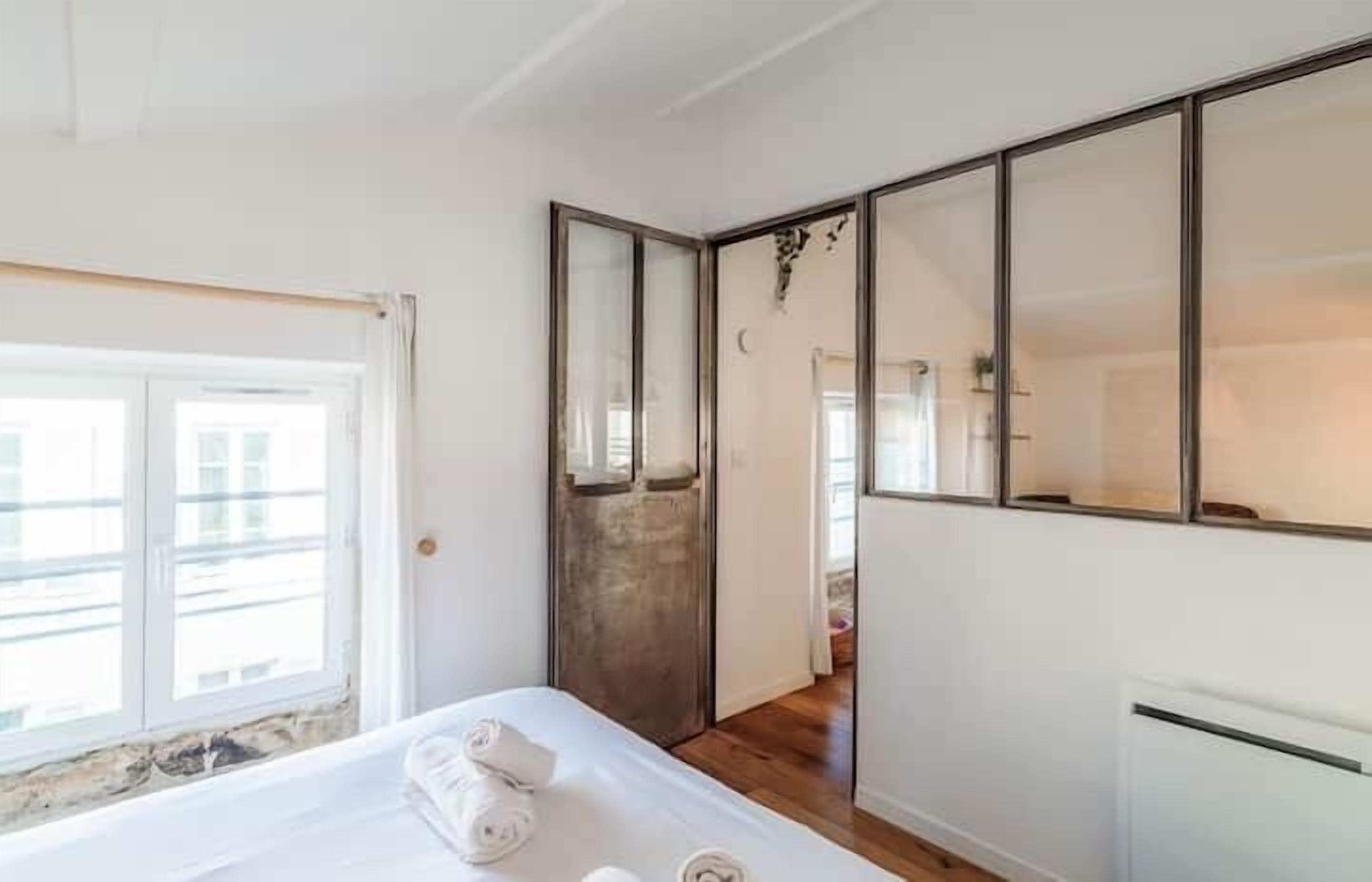 A bedroom with a bed, a wardrobe, and a large window.
