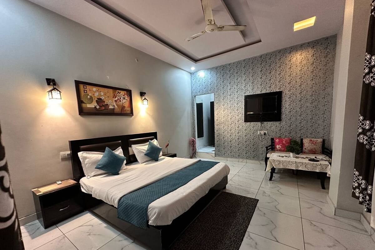 A modern bedroom with a large bed, bedside tables, a TV mounted on the wall, and a patterned wallpaper.