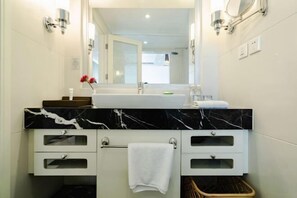 A modern bathroom with a marble countertop, a large mirror, and a towel rack. - Spring Downtown Hotel (Chengdu)