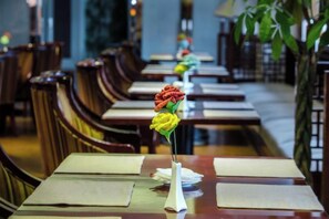 A restaurant with wooden tables and chairs, a vase with a flower centerpiece, and a long counter. - Spring Downtown Hotel (Chengdu)