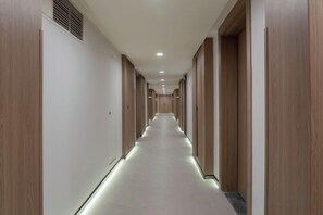 A long, narrow hotel corridor with wooden doors on both sides and a light-colored carpet. - Spring Downtown Hotel (Chengdu)