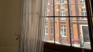 A room with a large window featuring a view of a red brick building. - Baker Street Apartments (London)