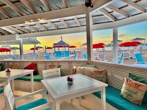 Un restaurante frente a la playa con terraza, vistas a la playa y un quiosco.