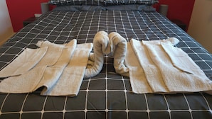 A bed with a checkered bedspread, two pillows, and a pair of folded towels. - Shefford Serenity Apartment In The Heart of Town (Shefford)