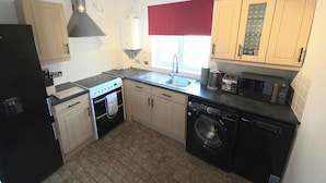 A compact kitchen with a stove, sink, microwave, and dishwasher. - Shefford Serenity Apartment In The Heart of Town (Shefford)