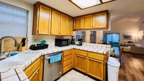 A compact kitchen with wooden cabinets, a microwave, and a dishwasher.