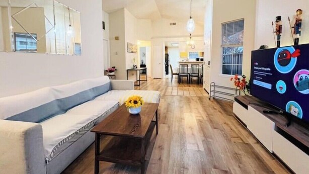 A modern living room with a sofa, coffee table, and a TV displaying a children's show.