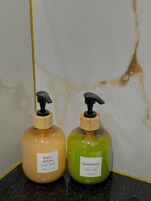 Two bottles of body wash and shampoo on a black countertop against a white wall with a yellow line. - Thanh Binh Premium Hotel (Ho Chi Minh City)